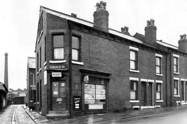 The junction of Pontefract Lane and Cross Aysgarth Mount. On the left is the entrance to Pottery Yard and a child and dog stand on the pavement. The building on the right begins with no 27, N Sheard's Grocers, closed till further notice but still advertising Woodbine, Capstan, Cadets and Player's cigarettes. Pictured in September 1966.