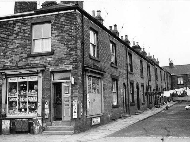 Barker Square pictured in August 1968. Number 1 in the foreground is a general store at the corner with Commercial Street. The shop window on Commercial Street is full of jars of sweets.