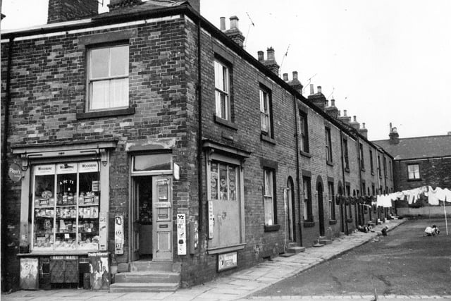 Barker Square pictured in August 1968. Number 1 in the foreground is a general store at the corner with Commercial Street. The shop window on Commercial Street is full of jars of sweets.