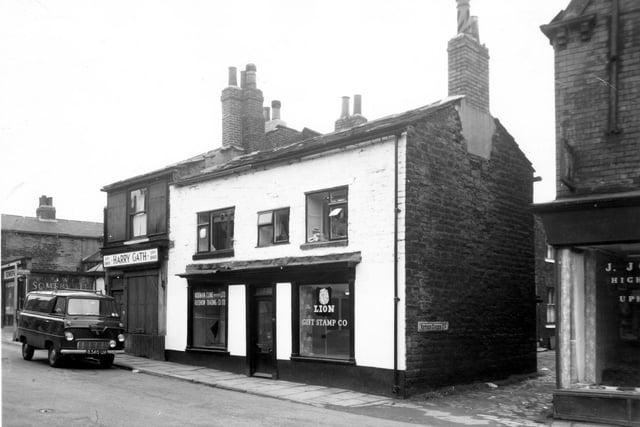 Harry Gath Fishmonger on Woodhouse Street followed by a double fronted shop used by several businesses including Norman Cline Builders Ltd, Gledhow Trading Co Ltd and Lion Gift Stamp Co. On the right is Nether Green Court, the edge of J. Johnson upholsterer's shop can bee seen.