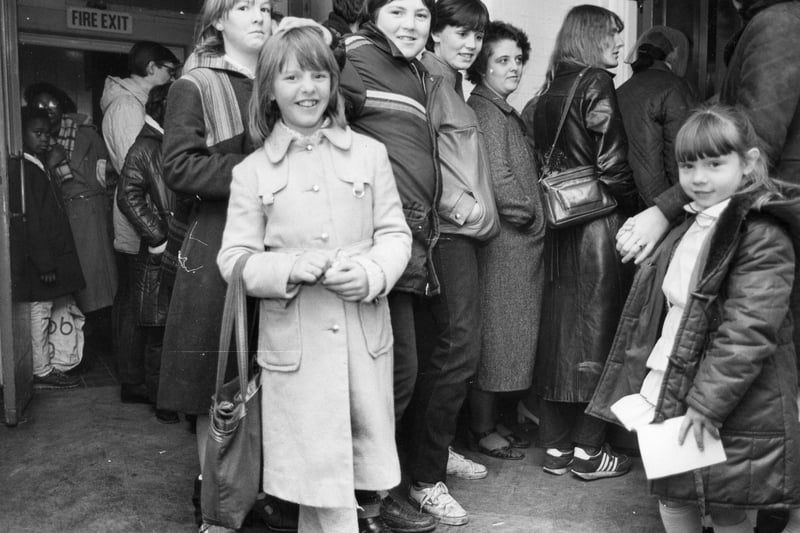 A photo taken outside Wykebeck School where people are queuing for the annual Wykebeck 'Family Allowance Toy Fair' held in December 1982. It was an opportunity to buy Christmas toys at reasonable prices thanks to donations by local firms and business fairs including 'Toy City'. The toys were a joint initiative between Social Services, the Probation Service and the Tenants' Association.