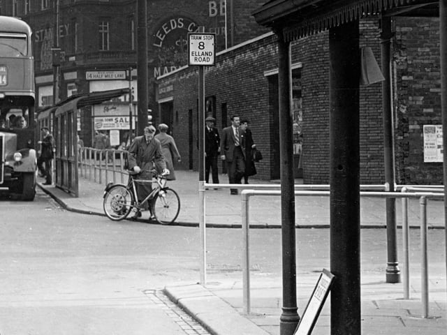 A photo taken from New Market Street looking towards Kirkgate Market, showing tram stop 8 to Elland Road in June 1955.. A bus stop can also be seen with bus 14 parked outside.