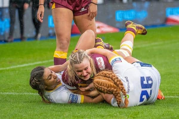 Huddersfield's Bella Sykes is held up by Leeds’ Sophie Robinson and Caitlin Casey during Rhinos' win in April.  Picture by Olly Hassell/SWpix.com.