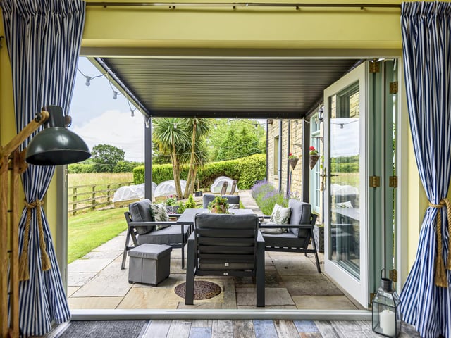 Bi-fold doors open to an outdoor sitting and dining area that is perfect for entertaining purposes.