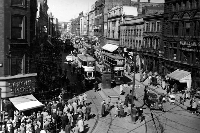 A view looking north from Boar Lane in April 1951. At the bottom left can be seen Saxone Shoes and a parade of shops. On the right is Walker & Hall, silversmiths. There are several trams in view. A police box is visible in the centre of the road.