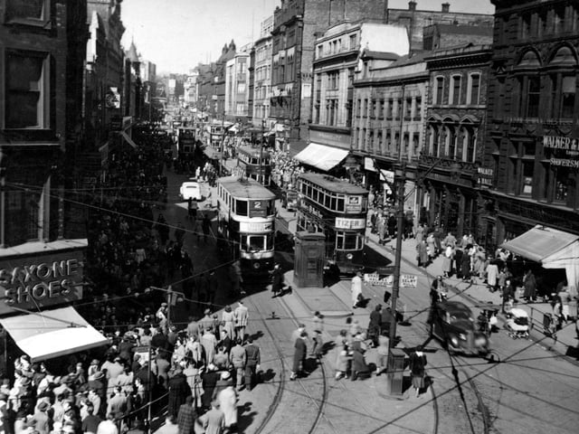 A view looking north from Boar Lane in April 1951. At the bottom left can be seen Saxone Shoes and a parade of shops. On the right is Walker & Hall, silversmiths. There are several trams in view. A police box is visible in the centre of the road.