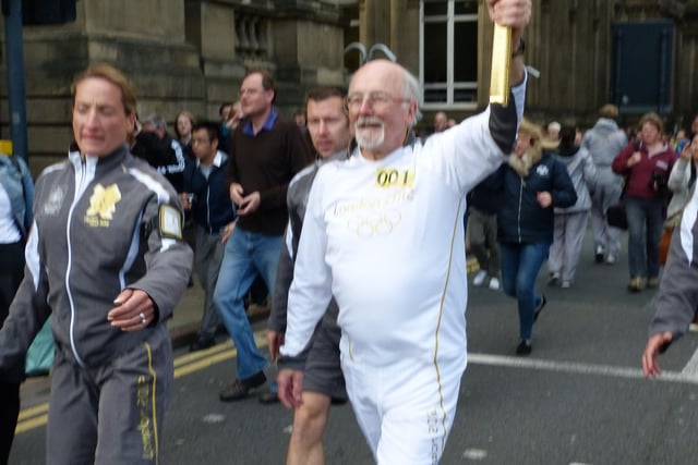 Mike Healey, as he arrives at Millennium Square carrying the Olympic flame on its progression through the city centre. Spectators line Calverley Street to catch a glimpse of the spectacle.