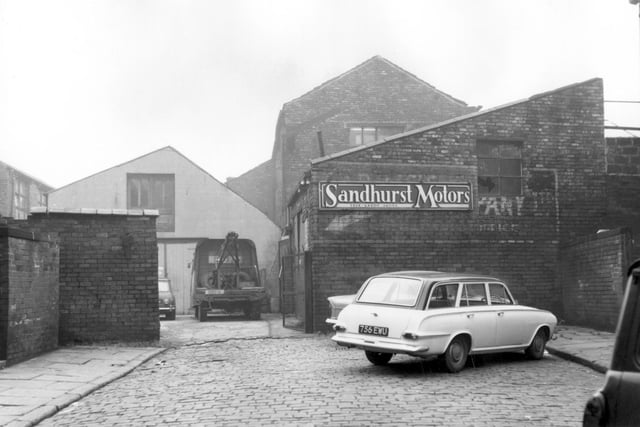 The entrance to Sandhurst Motors on Aysgarth Terrace in October 1966. The gate is open and inside the yard is a Mini Cooper and a tow truck, reg: O5O U. A white car is parked outside the yard on the cobbled street, reg 756 EWU