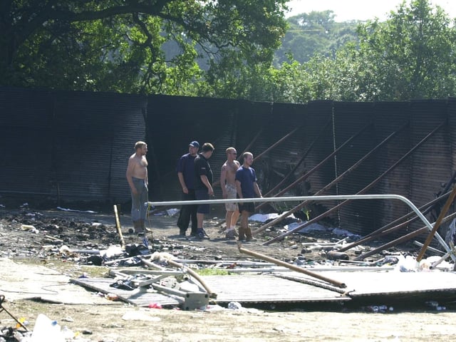 Workmen observe the damage to burnt out toilets at Temple Newsam in the aftermath of Leeds Festival