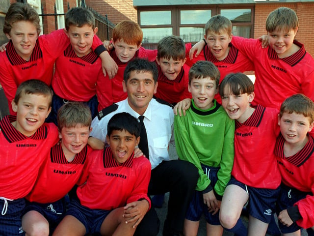 Firefighter Gino Webster with pupils at Holy Family R.C. Primary School in September 1997.  They are wearing the football kit Gino presented to the school, bought from money he won in a fitness competition.