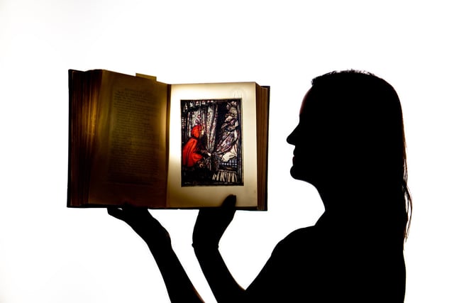 Rhian Isaac - Senior Librarian Specialist Collections looking at an illustration from Little Red Riding Hood, published in Grimm's Fairy Tales, Illustrated by Arthur Rackham. Photo: James Hardisty