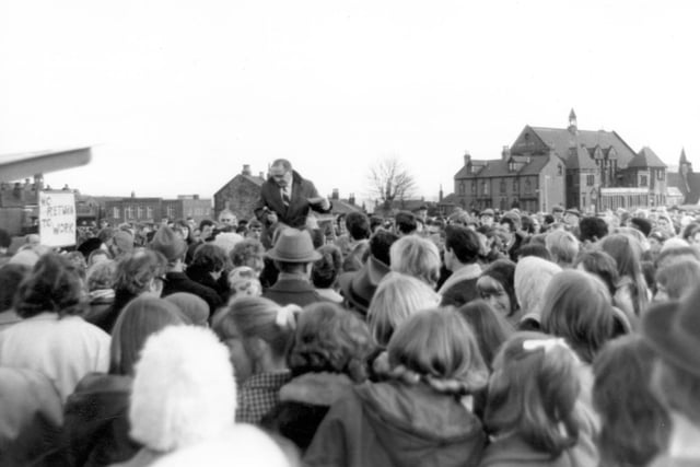 A meeting of striking workers on Woodhouse Moor in February 1970. Five thousand clothing factory workers rejected on the offer of immediate negotiations on their claim if they returned to work. Charlie Taylor was chairman of the unofficial strike committee. St Marks School can be seen in the background.