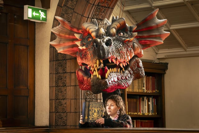 Librarian Heather Edwards reads a vintage Gulliver's Travels book with illustrations by Arthur Rackham, underneath a dragons head created by fantasy artist Anne Stokes. Photo: Danny Lawson/PA Wire