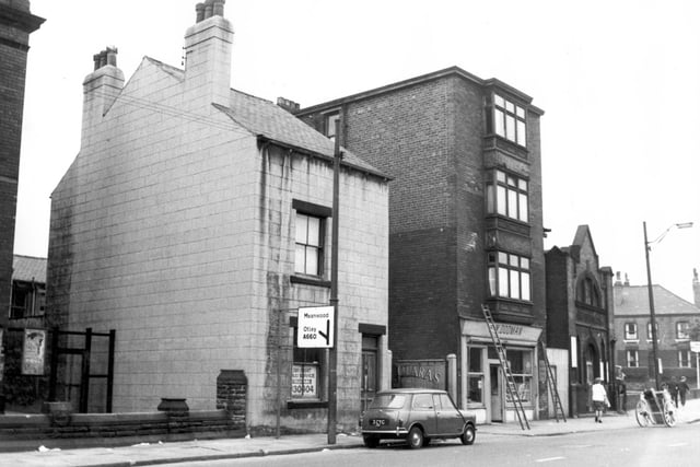Meanwood Road in August 1967. On the left is the wall of the Clowes Methodist Chapel. Next, house being used as an office for Telecabs Taxis. A Mini is parked in the road. This house and the yard on the right belonged to the Brizzolara family, who had an ice-cream business in the yard. In the afternoons and early evenings Tony Brizzolara would push an ice-cream cart through the area, he was partially sighted. This was number 171. Next 173, greengrocers shop run by Edward Dodman. Next, Salvation Army Meeting Hall, then forecourt of Yardleys Spa Garage. The house in view is the end of Servia Grove, junction with Cambridge Road.