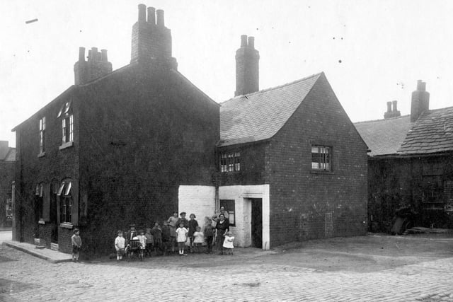 Children and adults pose for the camera at Finny Yard which was located on a corner plot of land between Low Road and Church Street. Pictured in August 1929.