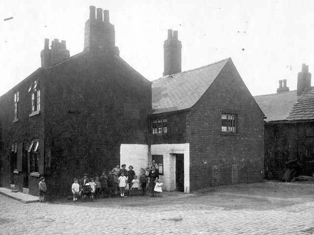 Children and adults pose for the camera at Finny Yard which was located on a corner plot of land between Low Road and Church Street. Pictured in August 1929.