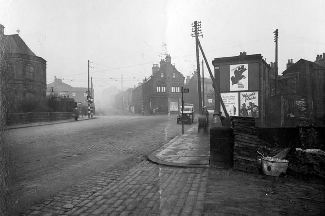 Kirkstall Goit on Bridge Road in January 1937. The Police station is on the left in centre of photograph. Midland Bank can be seen on corner. A Leeds City Transport bus stop is visible on the right.