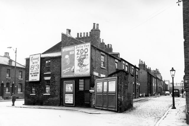 On the far left is Dewsbury Road with a man stood at the corner with Moor View Road in a suit and flat cap. On the left of Mount Place are some shared outside toilets with posters on the back asking people to join Britains strongest union and another informing union and another informing of job vacancies. On the right children can be seen playing in the cobbled street of Mount Place.