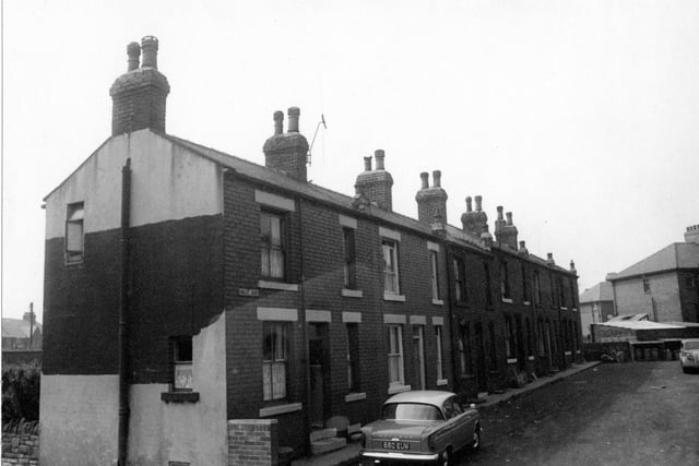 Tingley Court taken from Bridge Street in 1964. Street sign clearly visible, dustbins at end of street with backs of garages for adjacent properties on Britannia Road. Television aerial on roof of number 6 Hillman car reg: 660 EUM, parked in foreground.