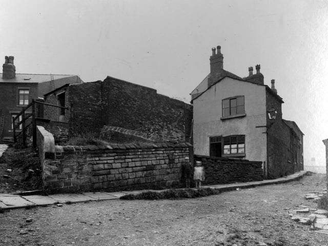 Part of Armley Road, showing tramlines, overhead cables, ornamental wrought iron street lamp, and large house with high wall around garden. Pictured in September 1937.