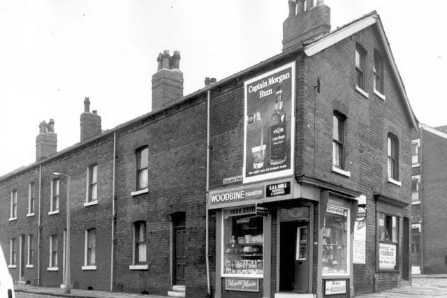 A row of terraced back-to-back houses with shops at the gable end. At no 59 is G & A Noble Groceries & Hardware, sellers of Woodbine, Cadets, Capstan and Player's Cigarettes. An advertising hoarding above the shop, promotes Captain Morgan Rum. The right rum for today's taste. On the right is Pontefract Lane Fisheries with Aysgarth Terrace, visible on the far right. Pictured in October 1966.