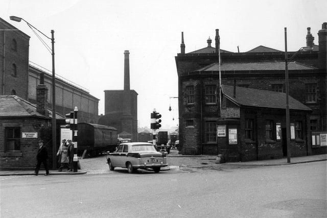 A view from Wellington Street into the British Railways Goods Yard. On the left is the junction with Northern Street. There are goods sheds on either side of the yard and a hoist in the background. The small building on the right is number 37 Wellington Street. These buildings were all part of the Central Station complex on a site between Whitehall Road and Wellington Street. This later became the site of the Royal Mail Headquarters and Aireside Retail Park.