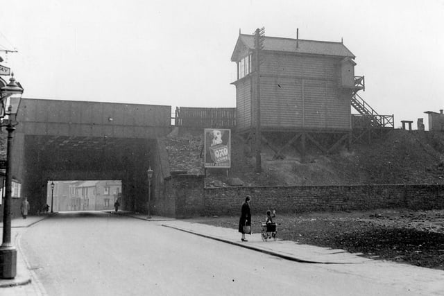 Spence Lane, bridge for London, North Western Railway, Leeds to Dewsbury Line. Holbeck signal box can be seen. Poster for OXO on the embankment. A child with dolls pram is waving towards the signal box. Pictured in August 1939.