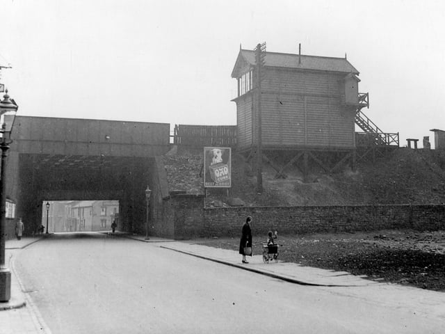 Spence Lane, bridge for London, North Western Railway, Leeds to Dewsbury Line. Holbeck signal box can be seen. Poster for OXO on the embankment. A child with dolls pram is waving towards the signal box. Pictured in August 1939.