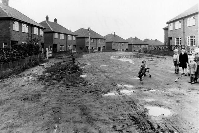 Newly built houses on Allerton Grange Gardens in August 1954. To the right is a group of small children. One is riding a tricycle.