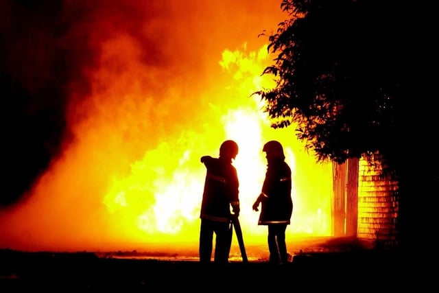 Firefighters look on as flames continue to shoot into the air from a factory fire on Kirkstall Industrial Estate in October 2003.