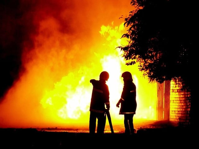 Firefighters look on as flames continue to shoot into the air from a factory fire on Kirkstall Industrial Estate in October 2003.