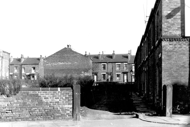 Artillery Place from Roundhay Road in the direction of Tramway Street. Houses on Artillery Place are visible along the right edge. In the background, the blind backs of numbers 20 and 22 Tramway Street are visible with the odd-numbered side behind.  Pictured in March 1966.