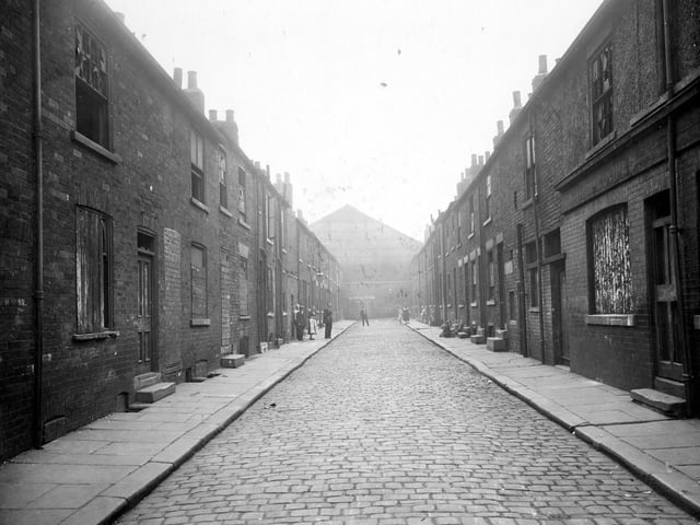 Mason Street in August 1935. Some of the two storey, brick built houses have boarded or bricked windows and doorways prior to demolition.  Centre of left hand side, yard for communal lavatory. The street ends in a wall, against which to left can be seen more outside lavatories. First on right, side of Masons' Arms public house (fronting onto Regent Street, number 87).