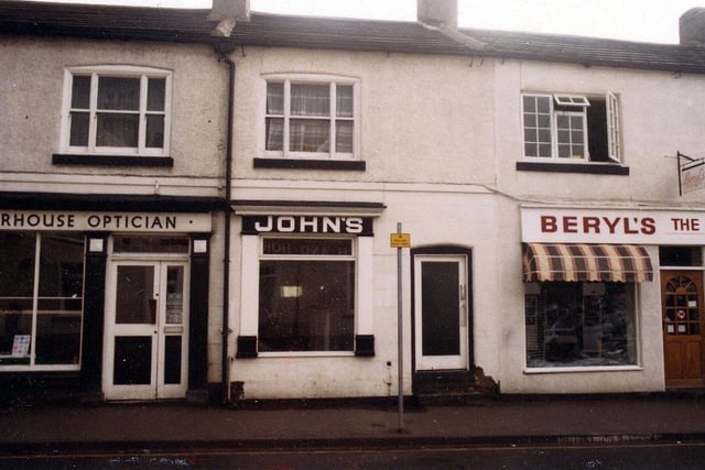 Shops on Commercial Street pictured in September 1984. In focus at no.35 is Moorhouse Optician, no.37 John's, men's hairdressing and no.39 Beryl's ladies and children's wear.
