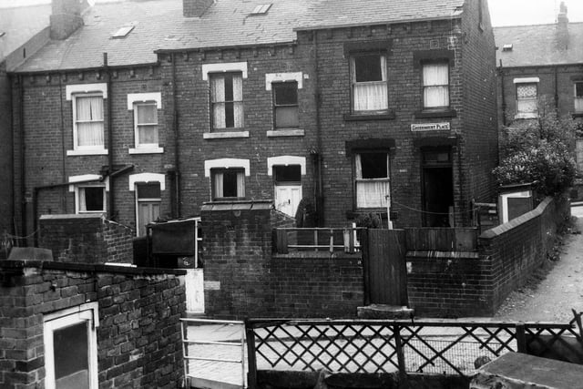 The rear entrances and yards to three through terraced houses on Greenmount Place in May 1971. These yards have been used to hang clothes lines and house coal sheds. On the far right of the image the road leads round to Greenmount Terrace.