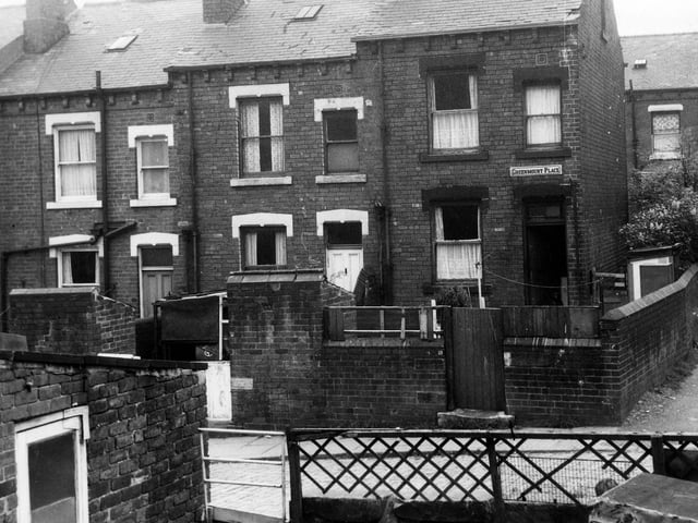 The rear entrances and yards to three through terraced houses on Greenmount Place in May 1971. These yards have been used to hang clothes lines and house coal sheds. On the far right of the image the road leads round to Greenmount Terrace.