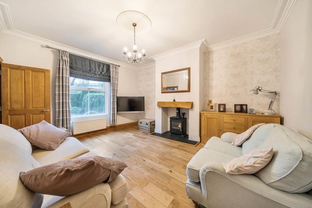 The attractive living room features period elements including large ceiling rose, cornicing, wood skirting boards and a recessed fireplace with wood burning stove.