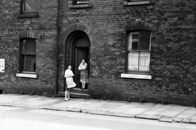 Two women in aprons stand at the entrance to a house on Belle Vue Road in the city centre in July 1964. The rear of this property faced onto Park Lane.