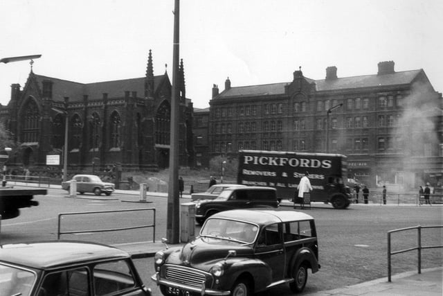 A view from the Queens Hotel to Park Row and Lower Basinghall Street in May/June 1964. On the left is Mill Hill Chapel in Park Row. Next to it is the former site of the 1875 Royal Exchange buildings which have recently been demolished. Clouds of dust can be seen as work is carried out. With the absence of the Royal Exchange the shop and business properties in Lower Basinghall Street, from centre to right, are now visible. These include the Del Rio Coffee Bar at number 12 Lower Basinghall Street.