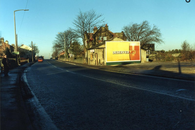 Bradford Road in Drighlington in December 1990. A fish and chip shop in the centre, with a large advertisement for Tetley's Bitter on the side. Further along the road is the Tempest Constitutional Club, and on the left hand side, the white building is the Painter's Arms public house.