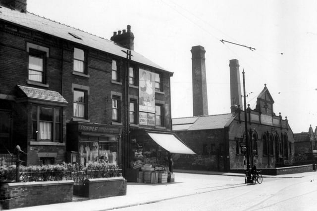Shops and houses on corner of Compton Road and Hudson Road in June 1939. Popple Ladies and childrens outfitters and greengrocers shop with awning up and boxes stacked on pavement. Burton's clothing factory is on opposite corner.A boy with a bicycle stands at edge of road by two belisha beacons.
