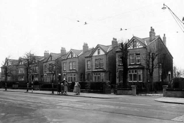 Street Lane, near its junction with Harrogate Road in January 1953. The houses are detached with gardens. In front, some people wait at a tram stop. Tram tracks are visible