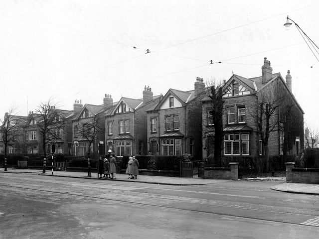 Street Lane, near its junction with Harrogate Road in January 1953. The houses are detached with gardens. In front, some people wait at a tram stop. Tram tracks are visible