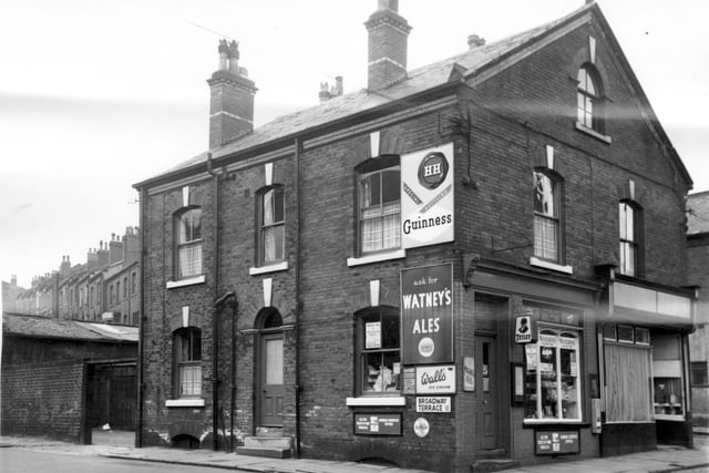 Two adjacent business premises on Malvern Road. Number 3 is an off licence with advertisements for Tetley, Guinness, Watney's Ales and Wall's Ice cream. Far left of photo is a yard with out buildings and next to it number 2 Broadway Terrace, living premises adjacent to the off licence. Houses in Westmount Place can be seen at a distance.