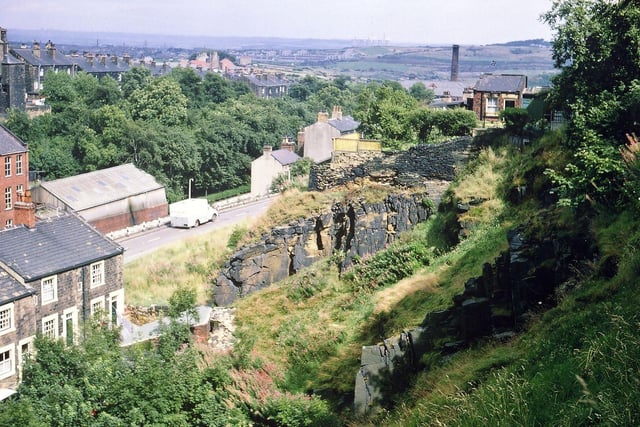 The face of the old town's quarry behind the Rock Inn from Troy Road. Part of Albert Road can be seen, aa well as Station Road Park, Crank Mill chimney, New Bank Street and parts of Leeds in the distance, with Skelton Grange Power Station on the far horizon.