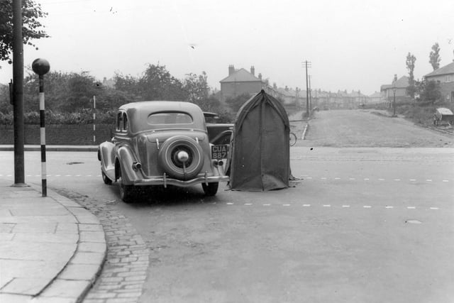 A car at the junction of Shaw Lane with Otley Road in July 1936. There is a telephone repair shelter in the road. Belisha beacons can be seen on the left. St Anne's Road is in the background.