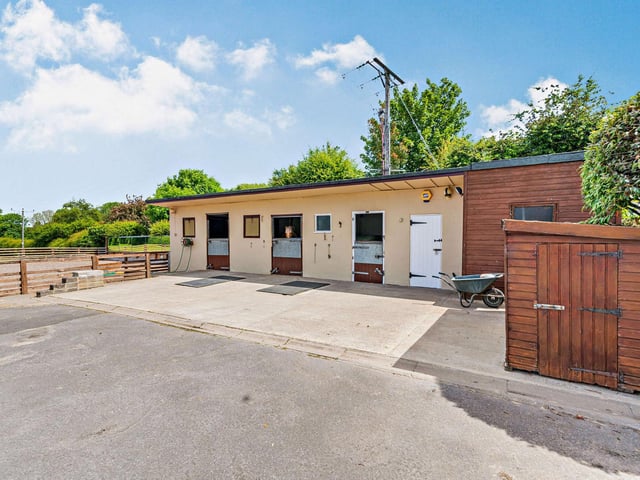 Three stables with tack and feed rooms form the stable block, adjacent to the menage and paddocks.