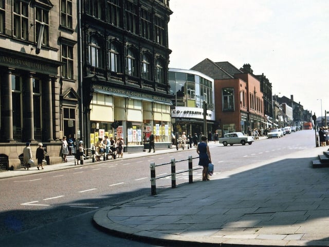 Afternoon shadows in Queen Street looking at the Morley Industrial Co-operative Society Buldings on the main bank side. The foreground shadow is from the Town Hall Tower. At the time, all three sections of the Morley Co-op were still open. It looks as if the furnishing section has been moved into Society House, many of the buildings along Albion Street have been closed including the grocery store, and a supermarket for food has been made in the 1899 building next to the bank. The 1957 Society House appears to sell furniture upstairs and the 1938 red-brick building (Emporium) was joined onto Society House and was probably selling the same type of goods at this time. Before the Morley Co-op closed down the food supermarket had moved into Society House and the Emporium.