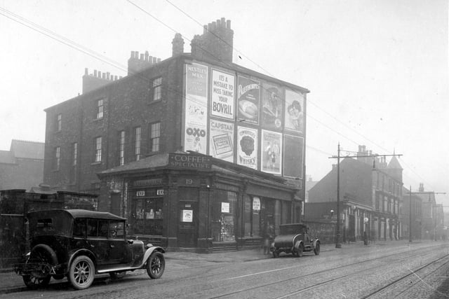 Roundhay Road which was the grocers shop premises of Walter Barker, with William Heaton, Boot and Shoe repairers at number 21. Advertising hoarding can be seen on gable end. Numbers 23, 25 and 27 is W. Mitchell Motors Ltd. Tramlines and overhead wires can be seen. Pictured in February 1930.