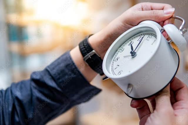 A stock image of a person adjusting a clock.